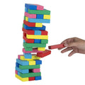 A hand is placing a red wooden block onto a colorful tower made of stacked toy blocks in red, blue, green, yellow, and pink, shown against a plain white background.