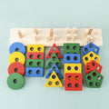 A colorful wooden shape-sorting toy set arranged on a pale blue background. The set includes a light natural wood peg board with pegs, round and rectangular pegs, and multiple matching wooden shapes in blue, green, yellow, and red with circular cutouts.