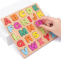 Wooden alphabet puzzle with colorful letters and a hand placing a letter on it.